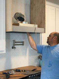 a man is lifting something from the cabinet above his kitchen counter top in order to get it ready for installation