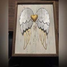 a painting with two wings and a heart in the middle is shown on a wooden frame