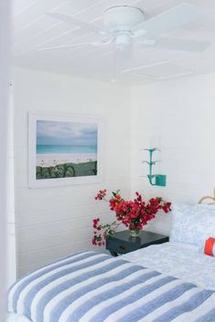 a white bedroom with blue and white bedding, red flowers on the nightstands