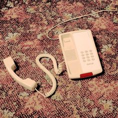 an old phone is laying on the floor next to it's corded telephone