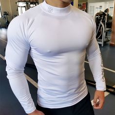 a man standing in a gym wearing a white shirt