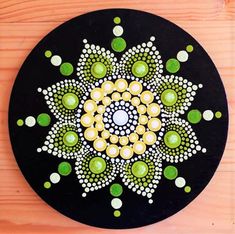 a black plate with green and white designs on it's side, sitting on a wooden surface