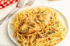 a white plate topped with pasta covered in gravy next to a fork and knife