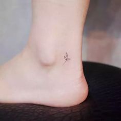 a small tattoo on the ankle of a woman's foot, with a single flower