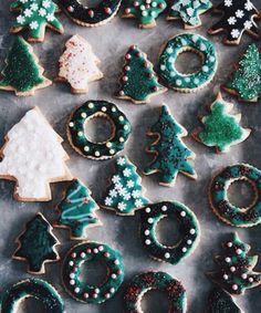 christmas cookies decorated with icing and sprinkles are arranged on a baking sheet