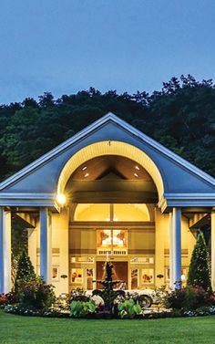 the front entrance of a hotel lit up at night with trees in the back ground