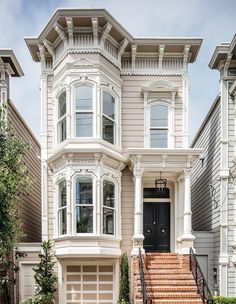 a two story house with stairs leading up to the front door