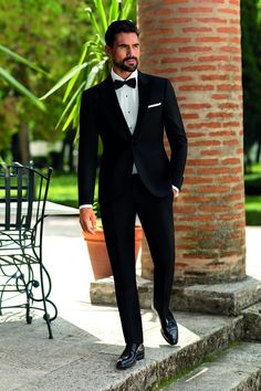 a man in a tuxedo standing on some steps