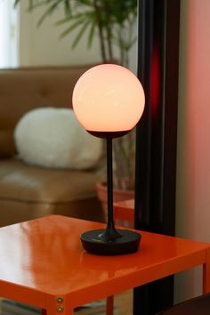 a table lamp sitting on top of a wooden table next to a brown couch in a living room