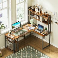 a computer desk with a laptop on it in front of a window and a rug