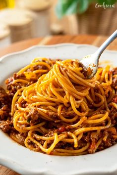 spaghetti with meat and sauce in a white bowl on a wooden table, ready to be eaten