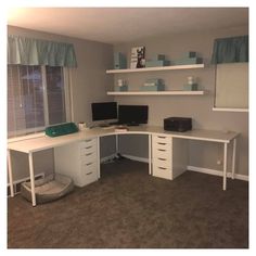 a room with two computer desks and shelves on the wall