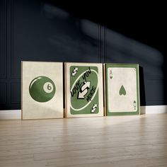 three green and white playing cards sitting on top of a hard wood floor next to a black wall