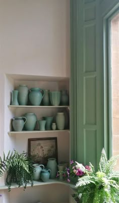 the shelves are filled with green vases and dishes