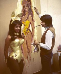 a man and woman in costume paint a painting