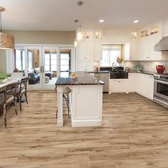 a large kitchen with white cabinets and wood flooring