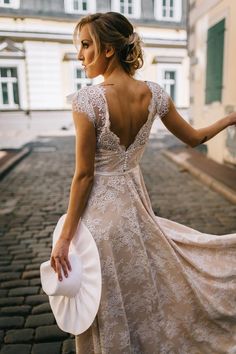 a woman in a dress and hat is walking down the street with her back to the camera