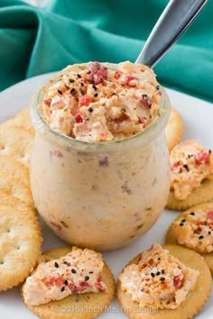 crackers and dip in a jar on a white plate with blue napkin behind it