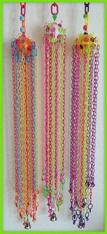 three colorful necklaces hanging from hooks with bells and beads attached to the ends,