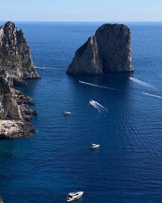 several boats in the water near two large rocks