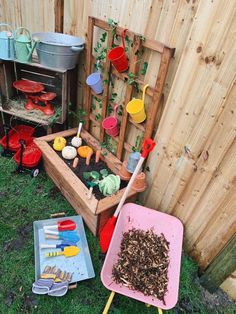 an outdoor garden area with gardening tools and potted plants in the ground next to a wooden fence