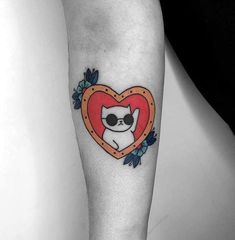 a cat in a heart shaped frame tattoo on the leg