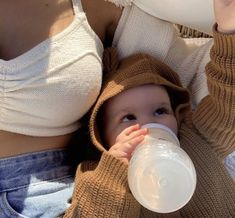 a baby drinking from a bottle while wearing a sweater