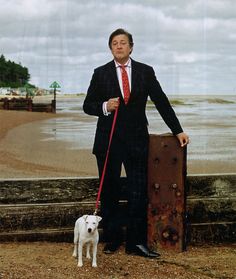 a man in a suit and tie standing next to a white dog on a leash