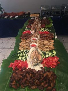 a long table filled with lots of food on top of a green leaf covered floor