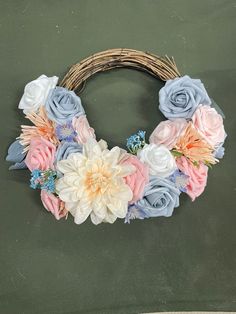 a wreath made out of fake flowers on top of a green surface with a wicker basket