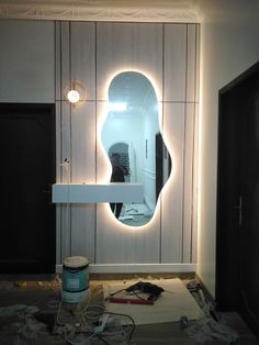 a mirror that is on the side of a wall next to a paint can and brush