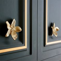 two black cabinets with gold handles and flowers on the door knobs, one has a flower in the middle