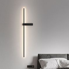 a bed with white sheets and pillows in front of a wall mounted light that has a cross on it