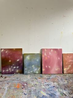 four different colored paintings sitting on top of a floor