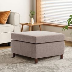 a living room with a couch, chair and ottoman on the floor in front of a window