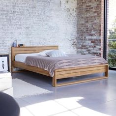 a bed sitting next to a window in a room with brick walls and flooring