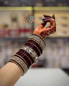 a woman's hand with bracelets and rings on her wrist holding something in the air