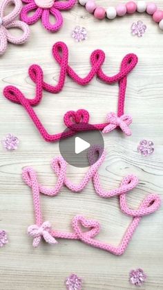 pink crocheted letters and beads on a wooden surface with the word love spelled out