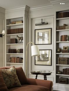 a living room filled with lots of bookshelves next to a couch and lamp