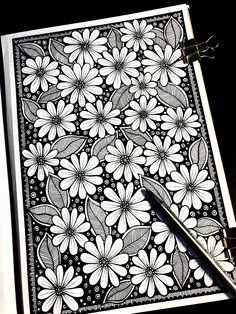 a black and white drawing of flowers on a piece of paper next to a pair of scissors