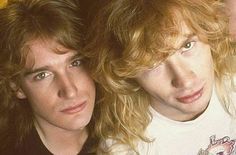 two young men with long blonde hair posing for the camera, one is looking at the camera