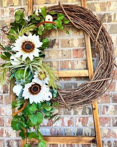 a wreath with sunflowers and greenery hanging on the side of a brick wall