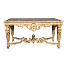 an antique console table with marble top and gold leaf decoration on the legs, against a white background