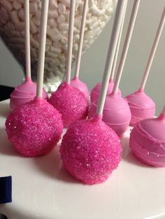 cake pops with pink frosting and sprinkles on a white platter