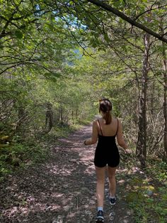 a woman walking down a trail in the woods