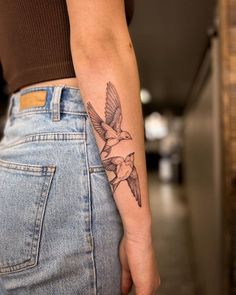 a woman's arm with a bird tattoo on the left side of her body