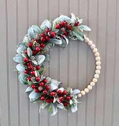 a wreath with red berries and greenery hanging on the wall next to a door