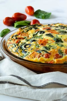 a casserole dish with spinach, tomatoes and cheese in it on a table