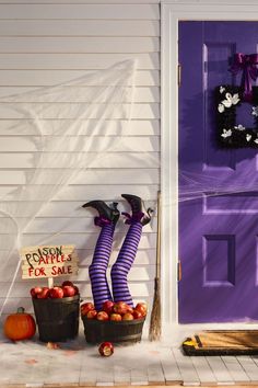 two buckets filled with apples sitting in front of a purple door and halloween decorations