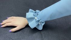 a woman's hand wearing a blue dress with a large bow on the wrist